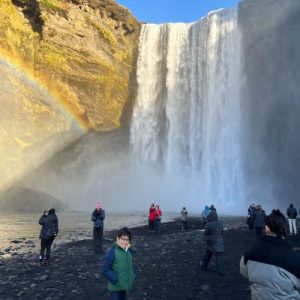 people taking photos by a waterfall