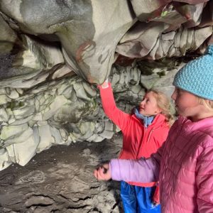 students feeling the rock formations in a cave